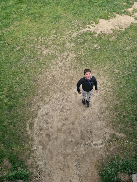 A man in a black shirt stands in a field with a patch of dirt in the middle of it.