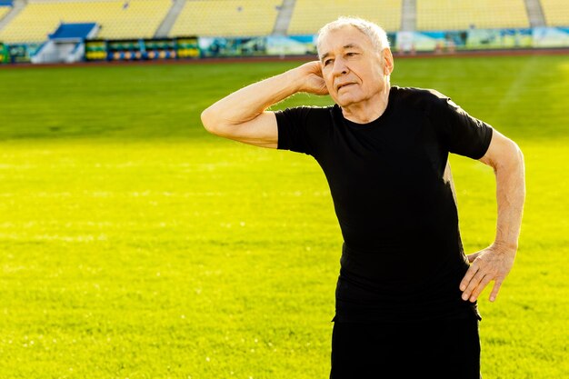 Foto un uomo con una camicia nera si trova su un campo sportivo con un cartello che dice 