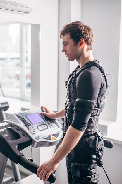 Man in black suit for ems training on treadmill