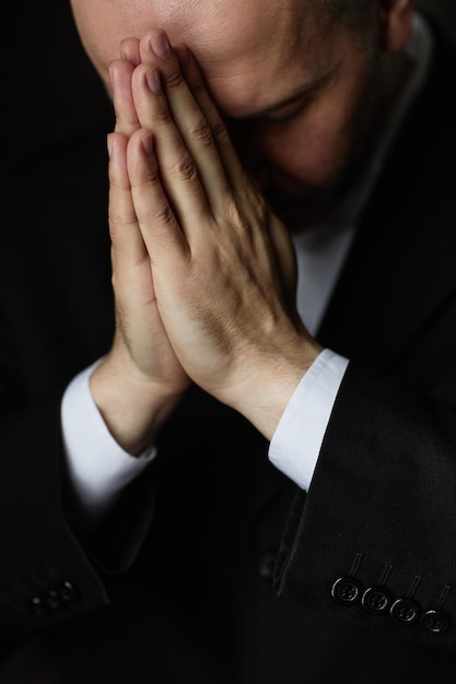 Man in black suit praying