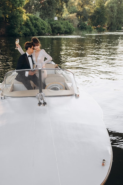 Man in a black suit and sunglasses hugs a woman on a yacht on a\
sunny day bride and groom