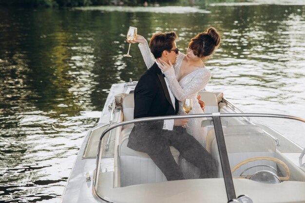 Man in a black suit and sunglasses hugs a woman on a yacht on a\
sunny day bride and groom