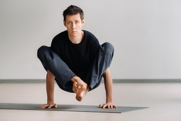 Photo a man in a black t-shirt trains lying down doing stretches in the gym.