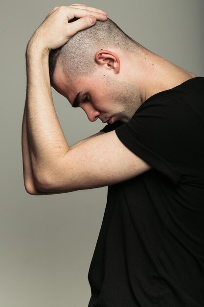 Man in black tshirt with both hands on his head