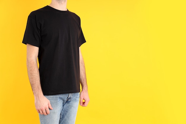 Man in blank black t-shirt on yellow background