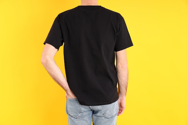 Man in blank black t-shirt on yellow background