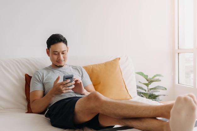 Man blij met de mobiele applicatie terwijl hij ontspant op zijn bank