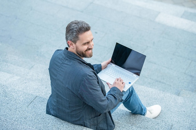 Man blogging online in the street back view man blogging online with pc outside