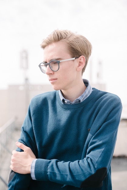 A man in a blue jumper poses.