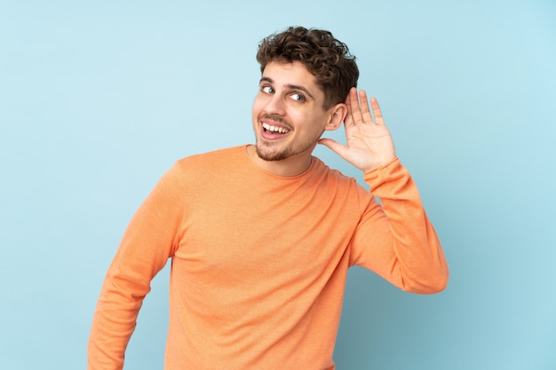 man on blue listening to something by putting hand on the ear