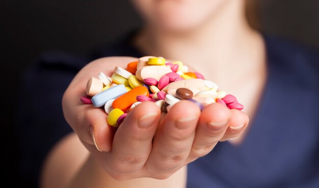 A man in blue medical clothing is holding a large number of medical pills