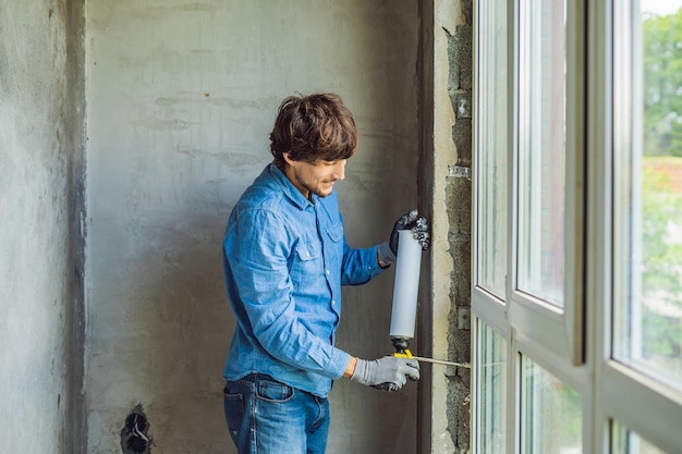 Man in a blue shirt does window installation Using a mounting foam
