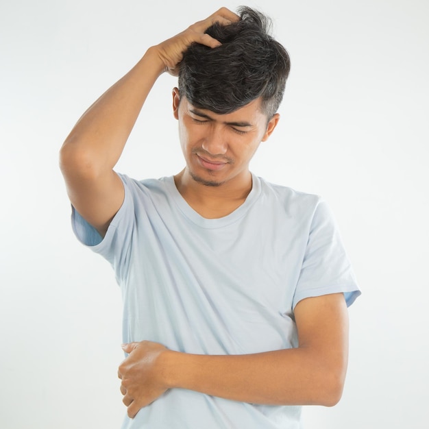 A man in a blue shirt has a hand on his head and has a headache.