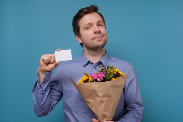 Photo man in blue shirt holding flowers as gift for his mother or girlfriend on birthday