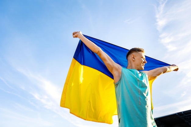 a man in a blue shirt holds a yellow and blue flag.