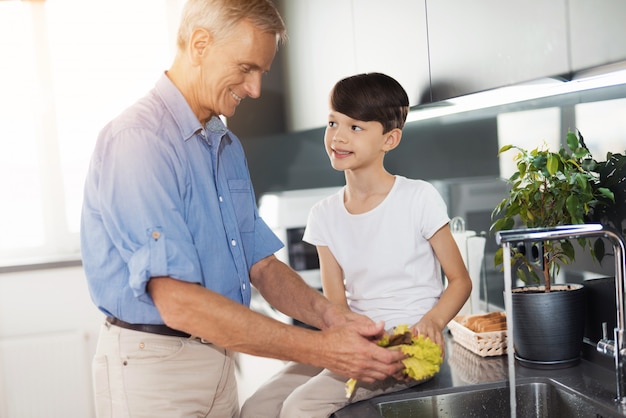 Man in a blue shirt is standing by the sink in the kitchen.