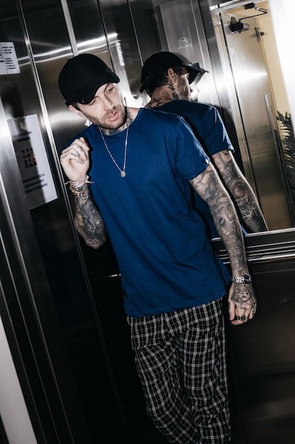 Photo a man in a blue shirt and plaid shorts walks in an elevator.