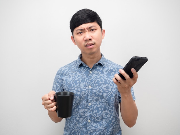 Man blue shirt talking with mobile phone and holding coffee cup feeling angry