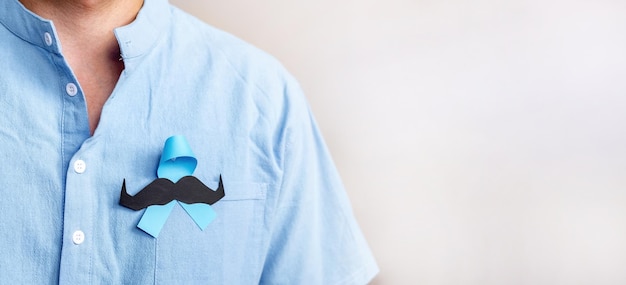 사람들의 생활과 질병을 지원하기 위해 파란색 리본과 종이 콧수염이 있는 파란색 셔츠를 입은 남자