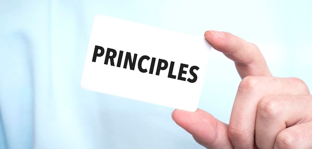 텍스트 PRINCIPLES 비즈니스 개념이 있는 카드를 들고 있는 파란색 스웨트 셔츠를 입은 남자