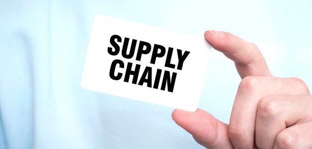 Человек в синей свитере с карточкой с текстом SUPPLY CHAIN бизнес-концепция