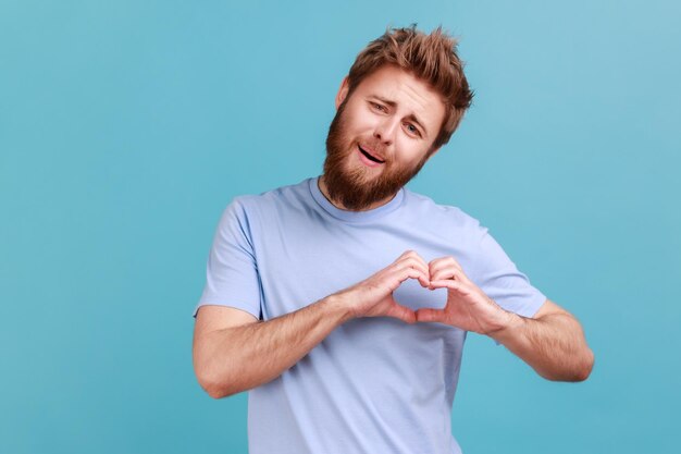 Man in blue Tshirt holding hands in shape of heart showing romantic gesture love confession