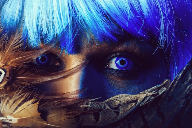 Man in blue wig behing feathers