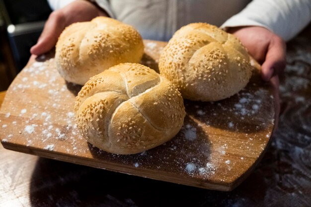 man board with buns with sesame . Flour is scattered on the table. The man made buns