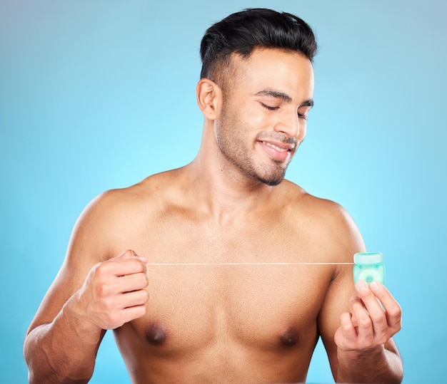 Man body or dental floss for grooming mouth hygiene maintenance or plaque removal help on blue background in studio Smile happy or flossing model and teeth product in healthcare wellness cleaning