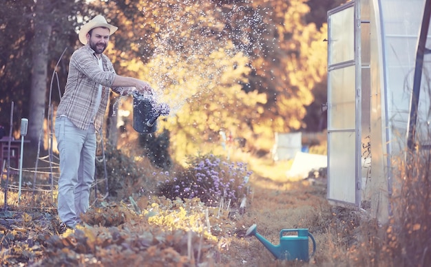 Man boer die 's avonds bij zonsondergang een moestuin water geeft