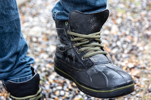 A man in boots stands on gravel close up