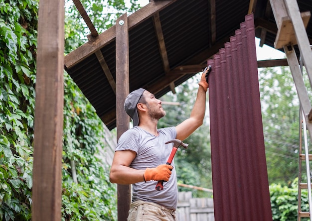 Man bouwt dak en houdt hamer en dakmateriaal vast