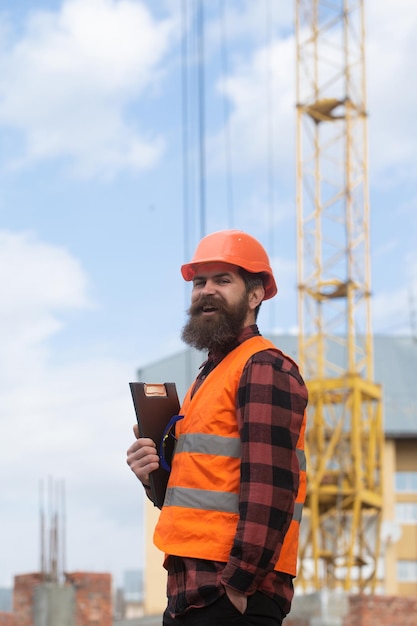 Man bouwvakker in helm poseert op bouwplaats industrieel thema