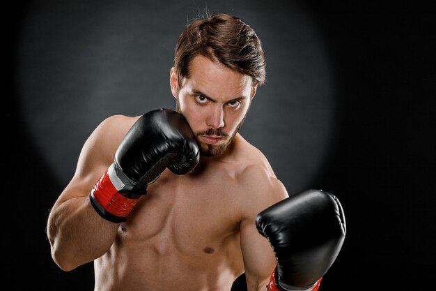 Мужчина в боксерских перчатках Мужчина боксирует на черном фоне Концепция здорового образа жизни