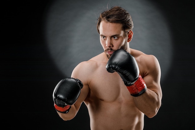 A man in Boxing gloves. A man Boxing on a black background. The concept of a healthy lifestyle.