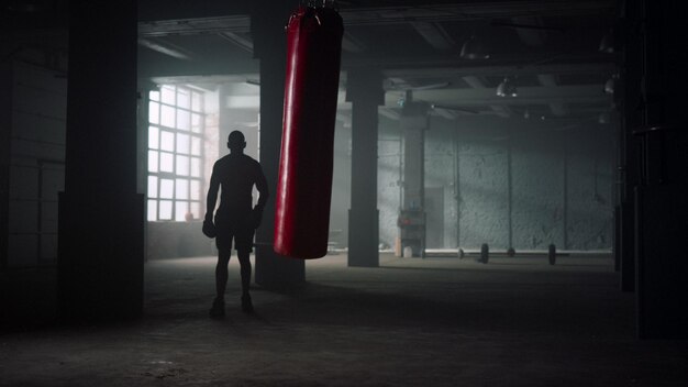 Foto uomo in guanti da boxe che cammina in un loft atleta che fa allenamento di boxe