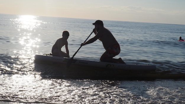 A man and a boy are paddling in a boat.