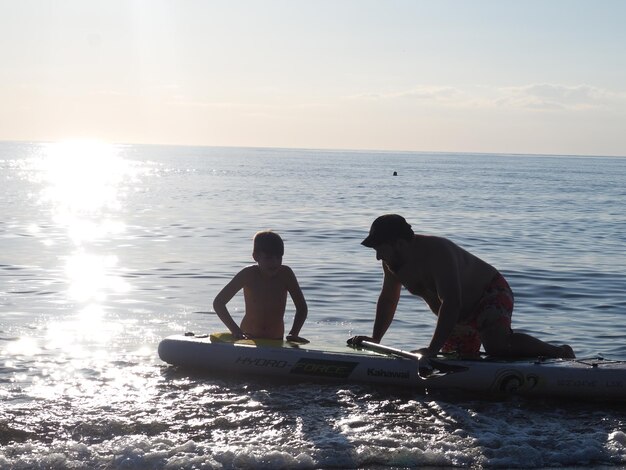 A man and a boy are in the water with a surfboard that says'surfboard'on it