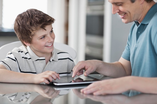A man and a boy seated looking at a digital tablet and using the touch screen