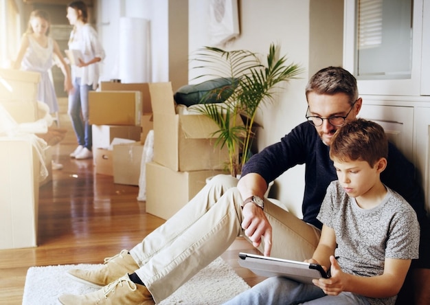 Foto uomo ragazzo e tablet che giocano e rilassano una pausa dal disimballaggio e dal trasloco nella nuova casa padre figlio e tecnologia wireless con proprietà immobiliari e riposo con videogiochi online e legame