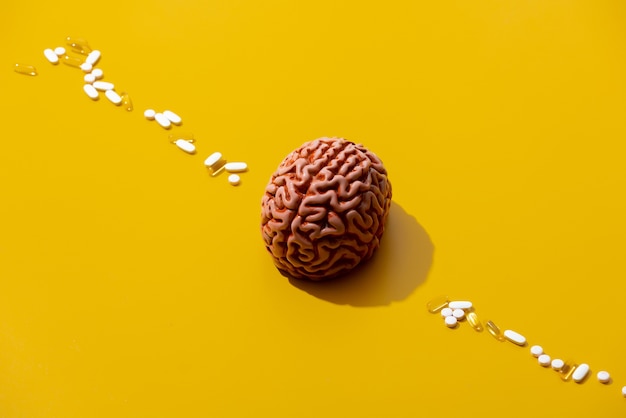 Man brain and pills around on yellow surface