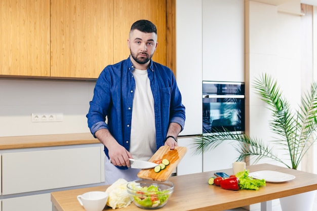 man brengt de dag thuis door met het bereiden van ontbijt in de keuken met groenten een man in huiskleren en met een baard