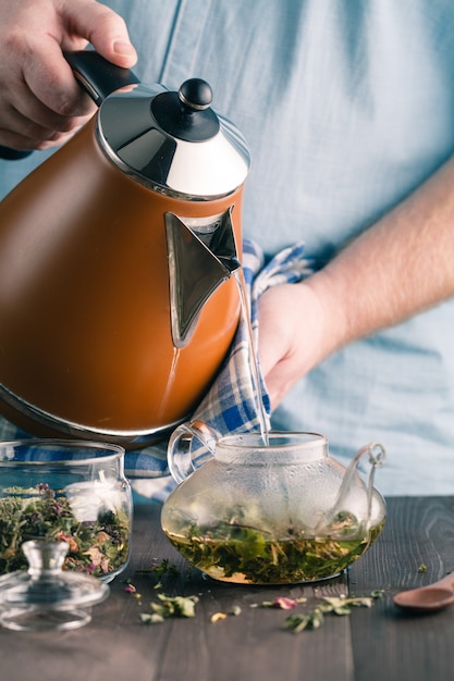 Фото Мужчина заваривает травяной чай в чайнике