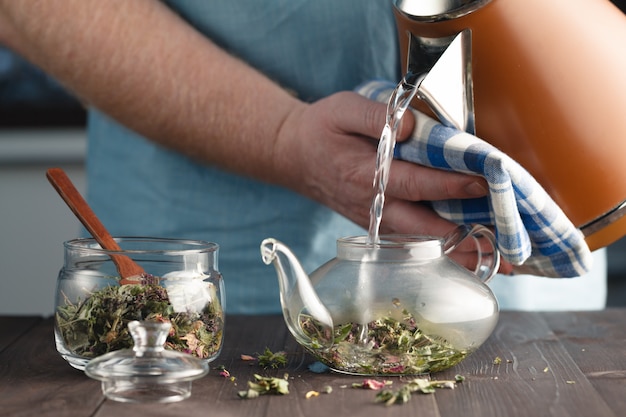 Photo man brews herbal tea in a kettle