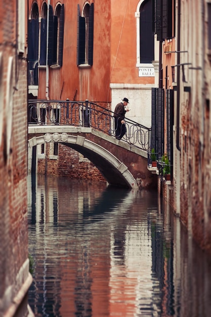 Man on the bridge of one of the Venice canals