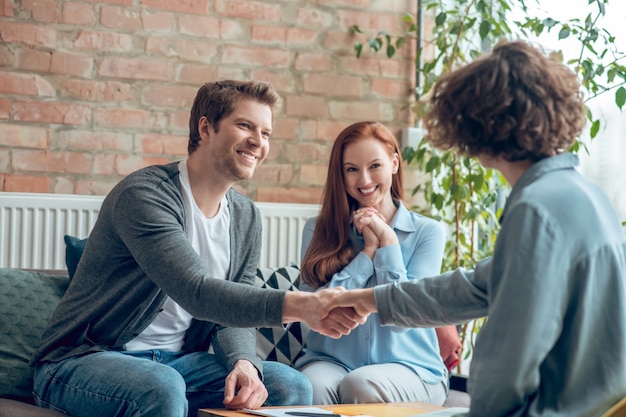 Man and broker shaking hands in office