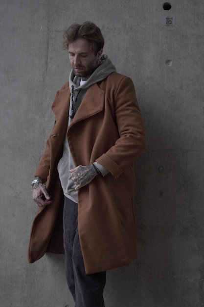 Foto un uomo con un cappotto marrone giace a terra con le mani sui fianchi.