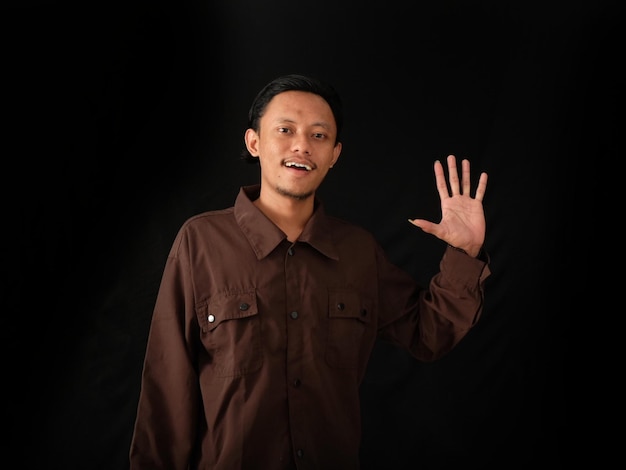 A man in a brown shirt is waving his hand.