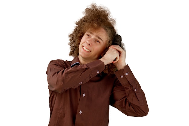 man in a brown shirt uses a metal round comb