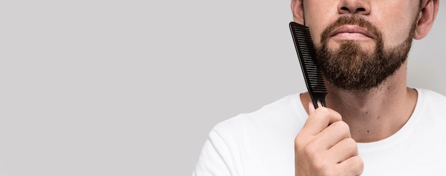 Man brushing his beard with copy space